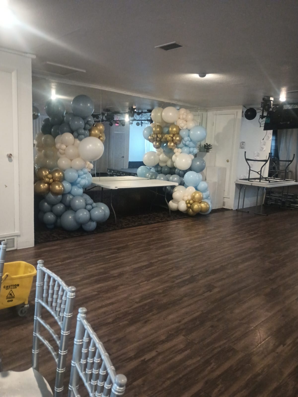 Montaje con arco de globos azules, blancos y dorados