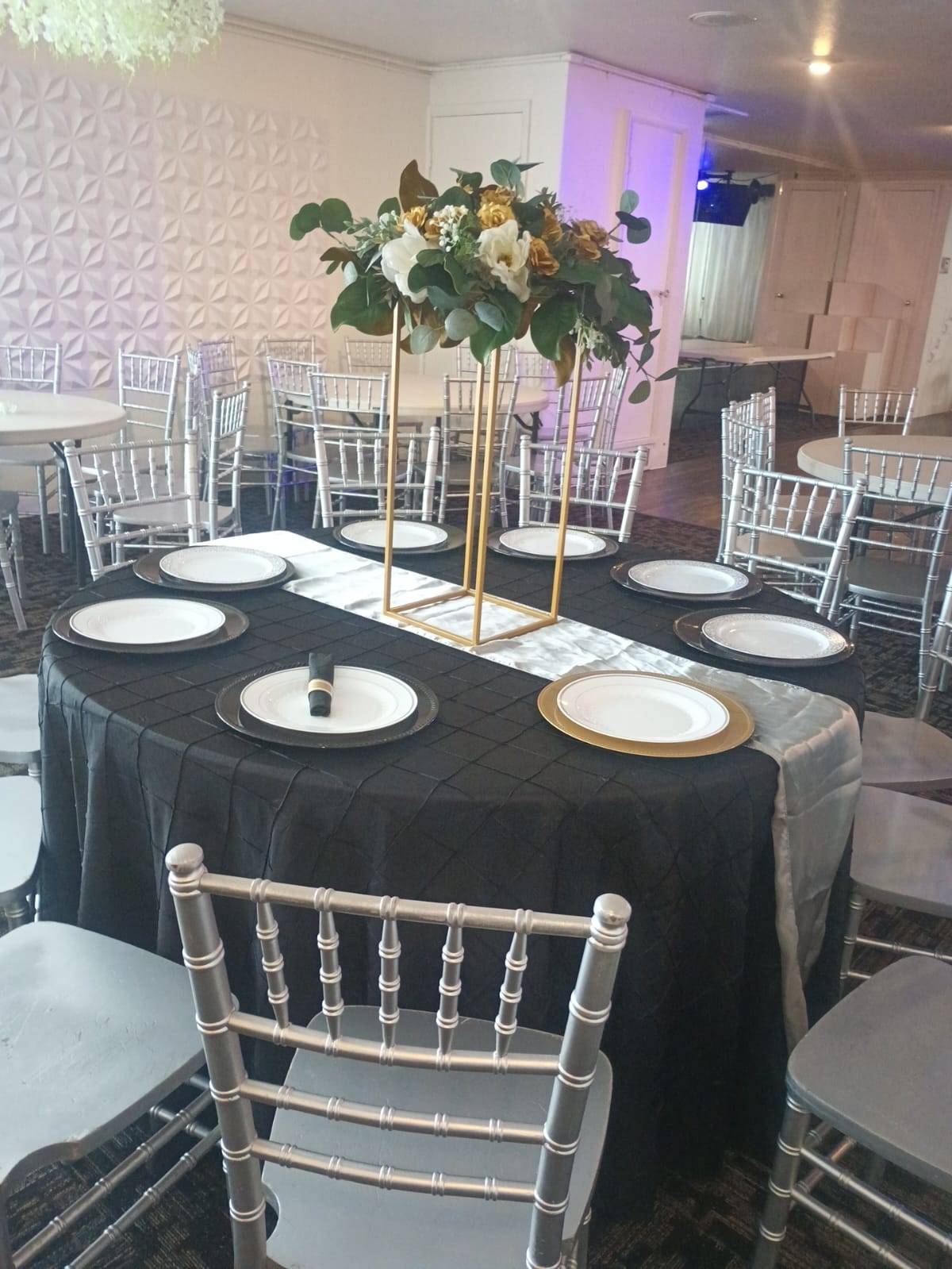 Mesa elegante con vajilla negra, dorada y centro floral