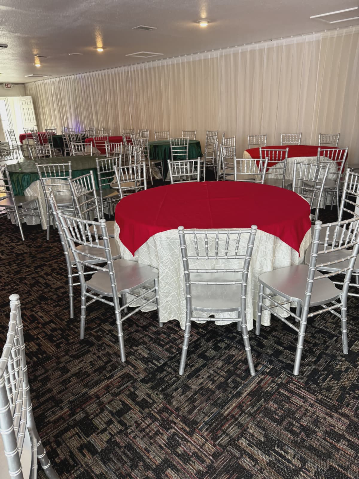 Mesas redondas con manteles rojos y sillas Chiavari plateadas
